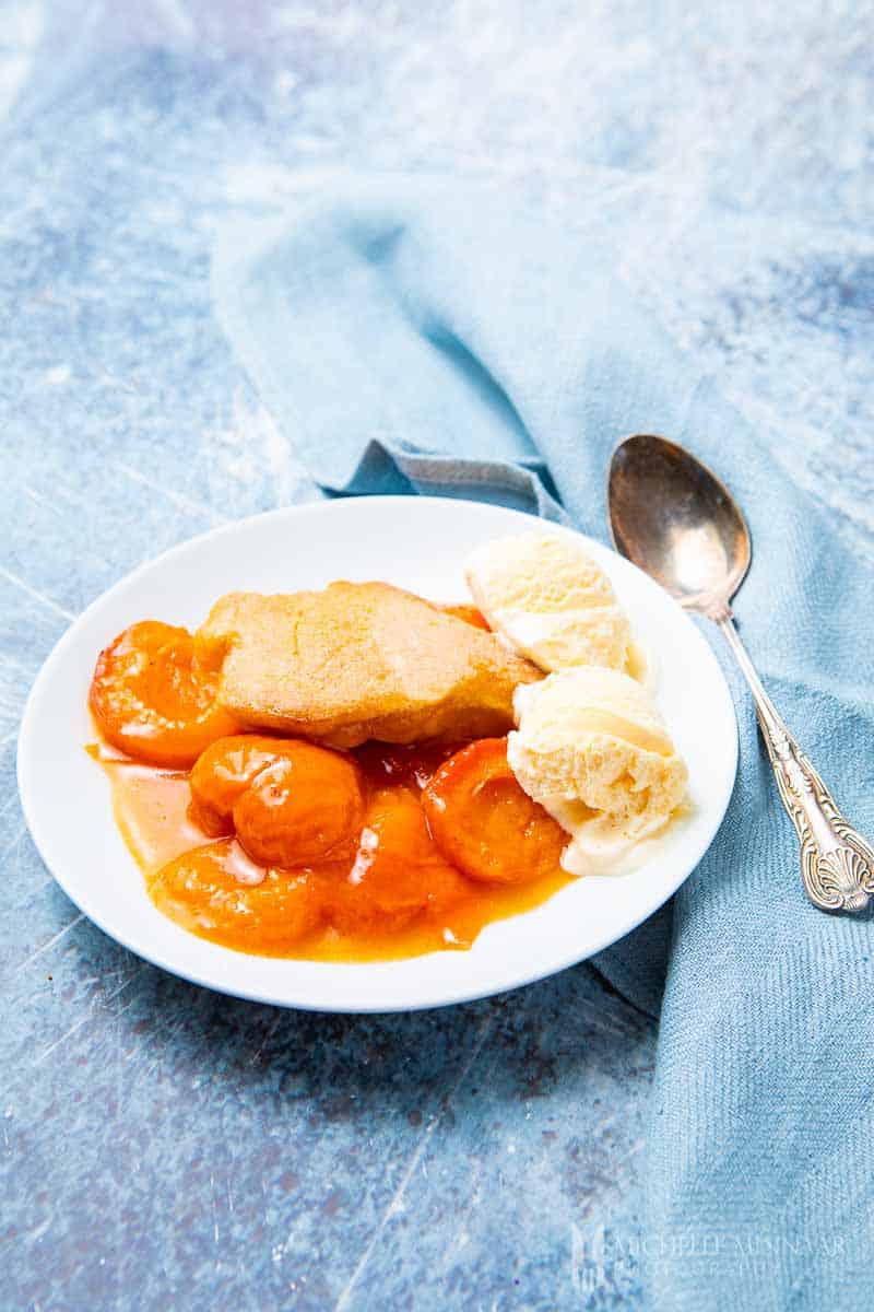 A plate of apricot cobbler with a scoop of ice cream 