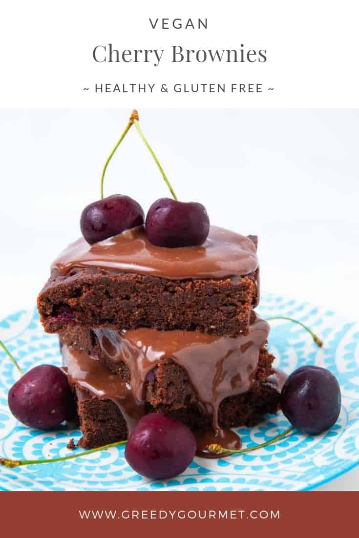 Two cherry brownies covered in melted chocolate and fresh cherries