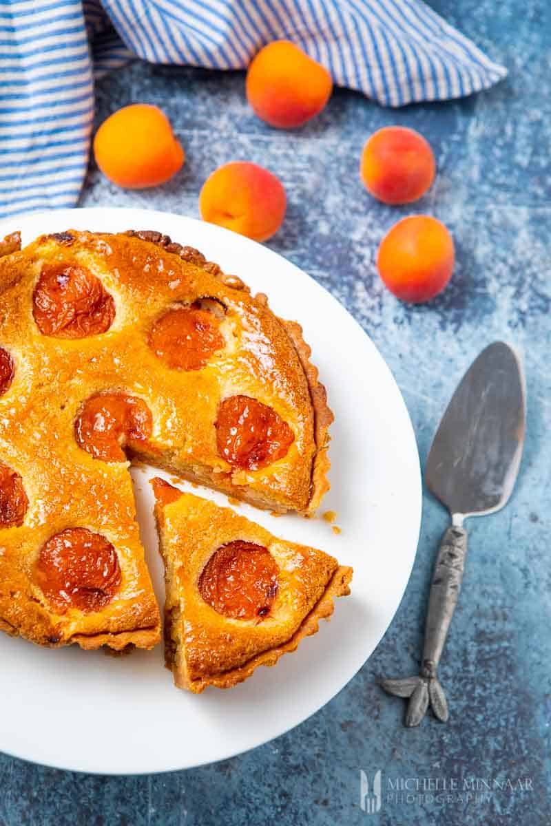 A full apricot tart with a slice cut out 