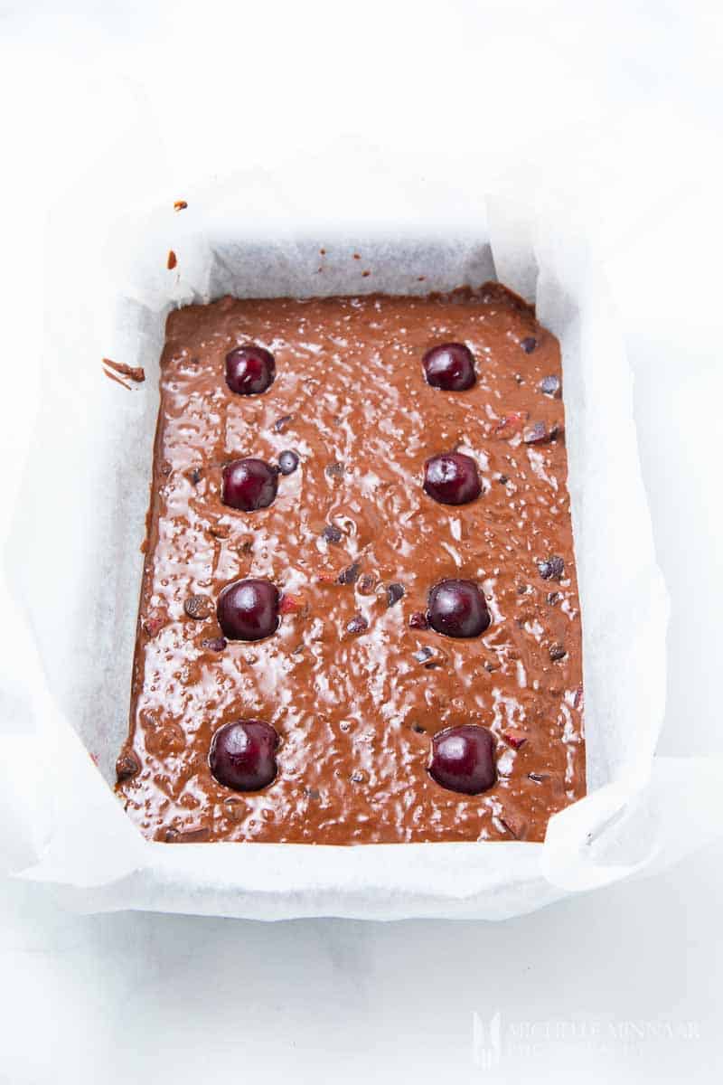 Liquid cake batter with fresh cherries in a baking pan 