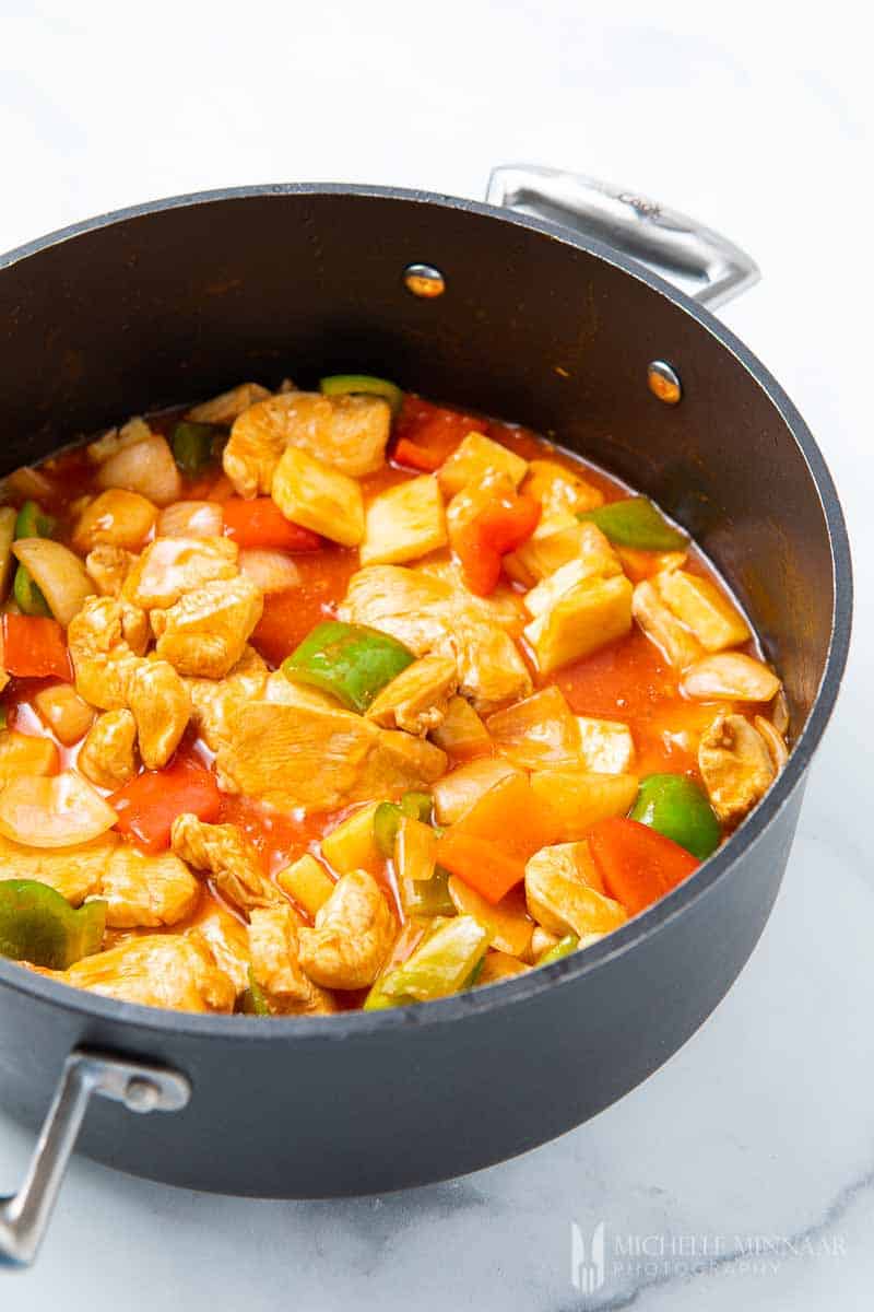 Chicken, peppers, pineapple simmering in a pot