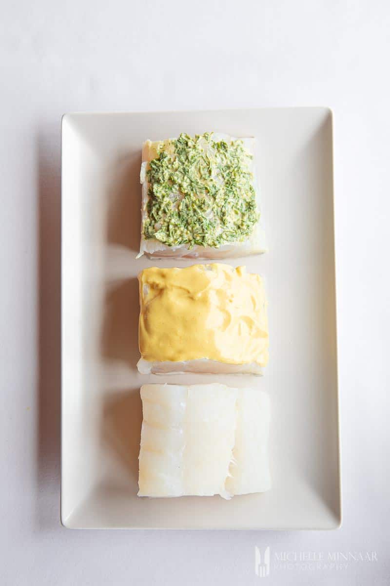 Three pieces of cod with green and yellow sauce