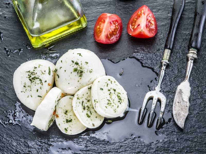 Slices of mozzarella cheese in oil and tomatoes