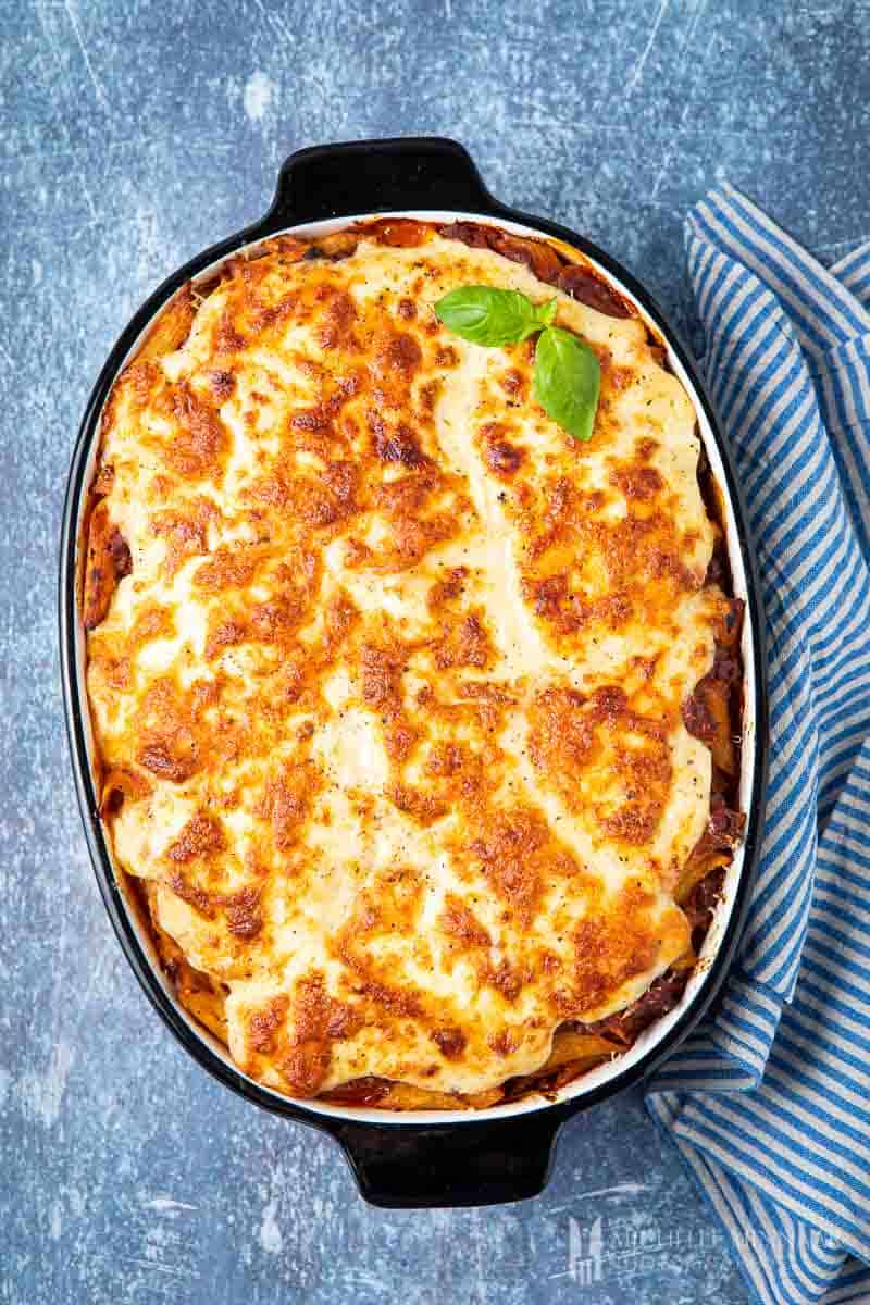 baked pasta dish in black baking dish with blue background