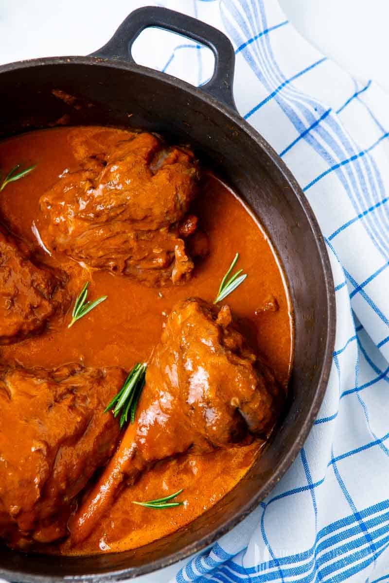 Slow cooker lamb shanks in a pot simmering 