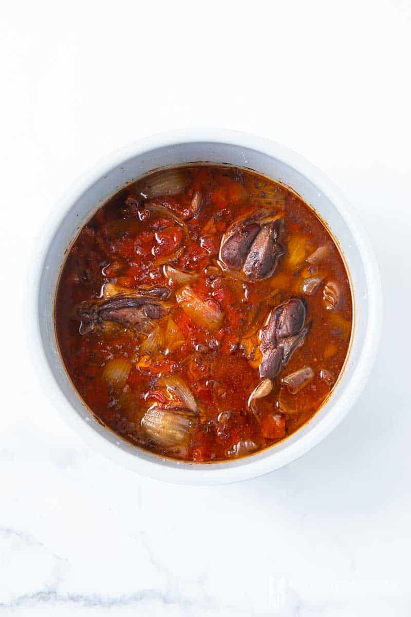 Aerial view of slow cooker lamb shanks in a pot simmering 