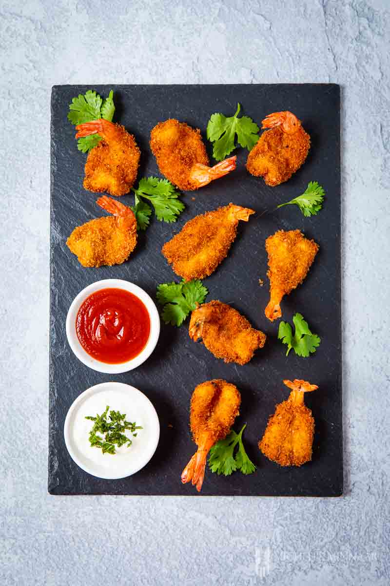 king prawn butterfly on a black board with dipping sauce 