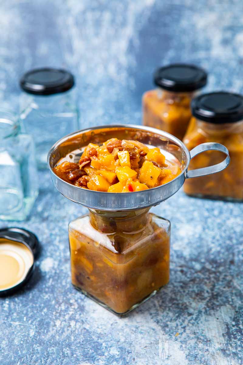 using a funnel to put chutney into a sterilized jar.