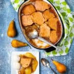 Casserole dish of pear cobbler with a slice removed with ice cream