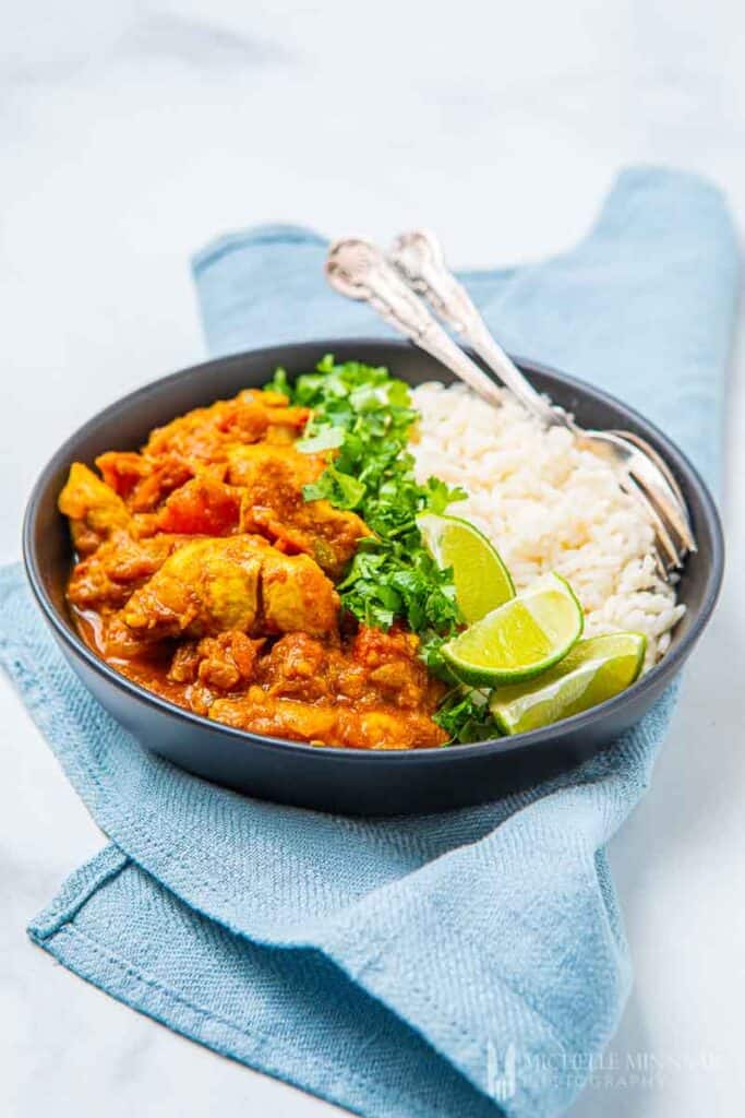 Bowl of chicken korai with white rice and limes in a bowl