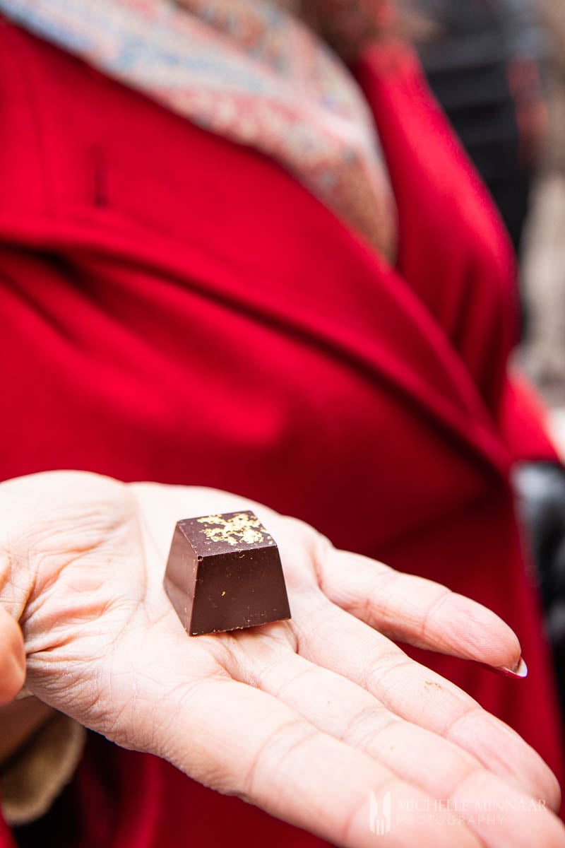 A lady in a red coat, holding a balsamic vinegar chocolate.