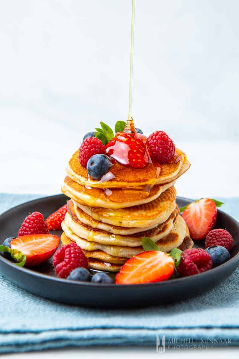 Syrup being poured onto a pile of crempog