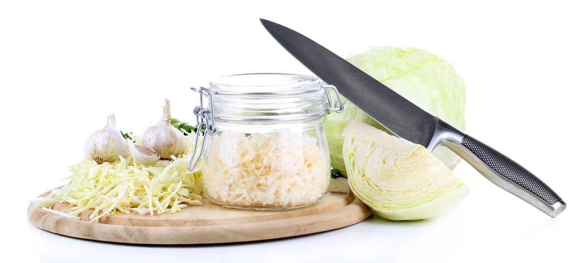 Glass jar of sauerkraut, sliced cabbage and a knife