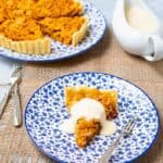 Whole cornflake tart with a slice removed and a dollap of creme on top