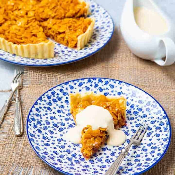 Whole cornflake tart with a slice removed and a dollap of creme on top