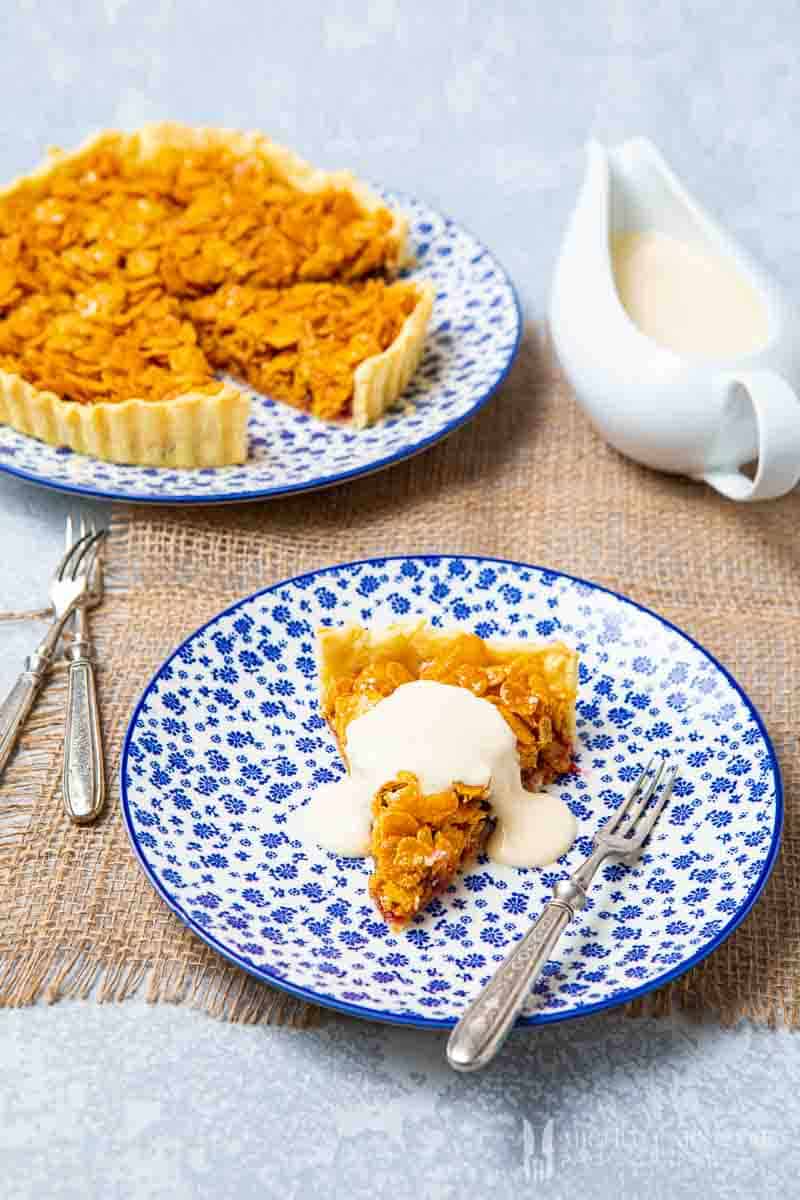 Whole cornflake tart with a slice removed and a dollap of creme on top