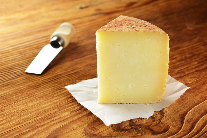 Triangular chunk of yellow vacchino romano cheese.