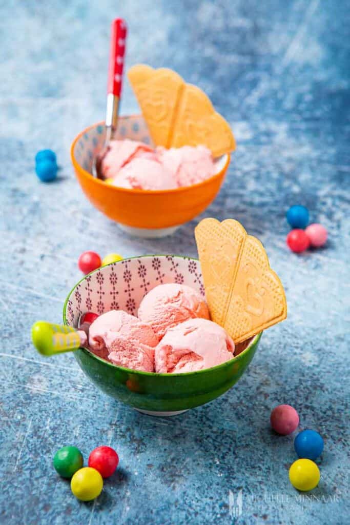 Two bowls of pink ice cream with wafers