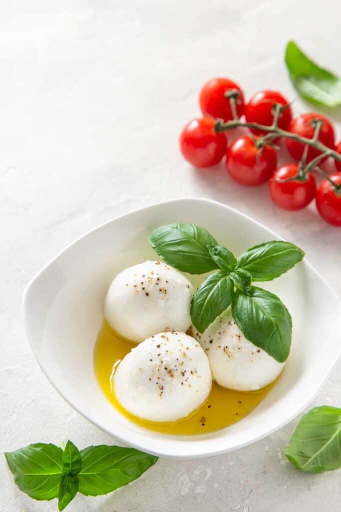 Balls of fresh mozzarella cheese in oil and basil