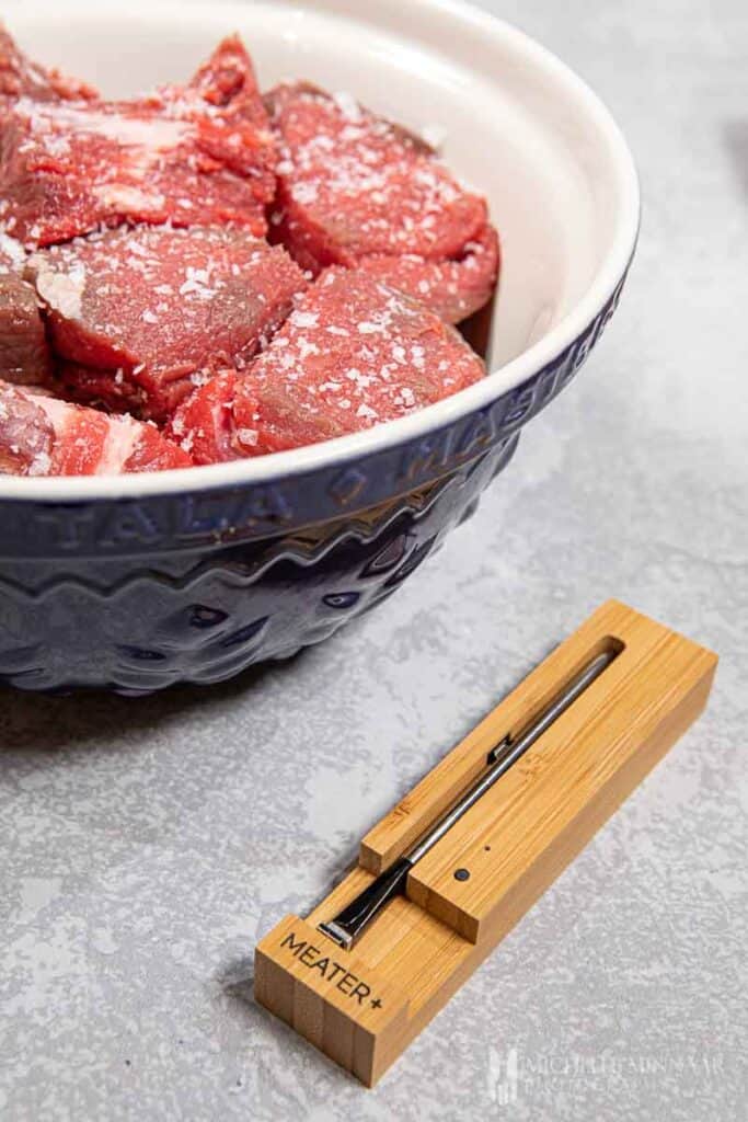 Raw ribs in a bowl and a meat thermometer