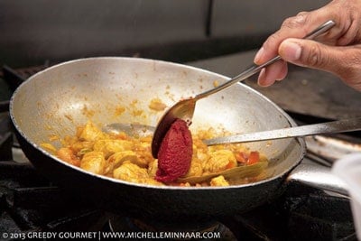 Tomato puree being added to the pan