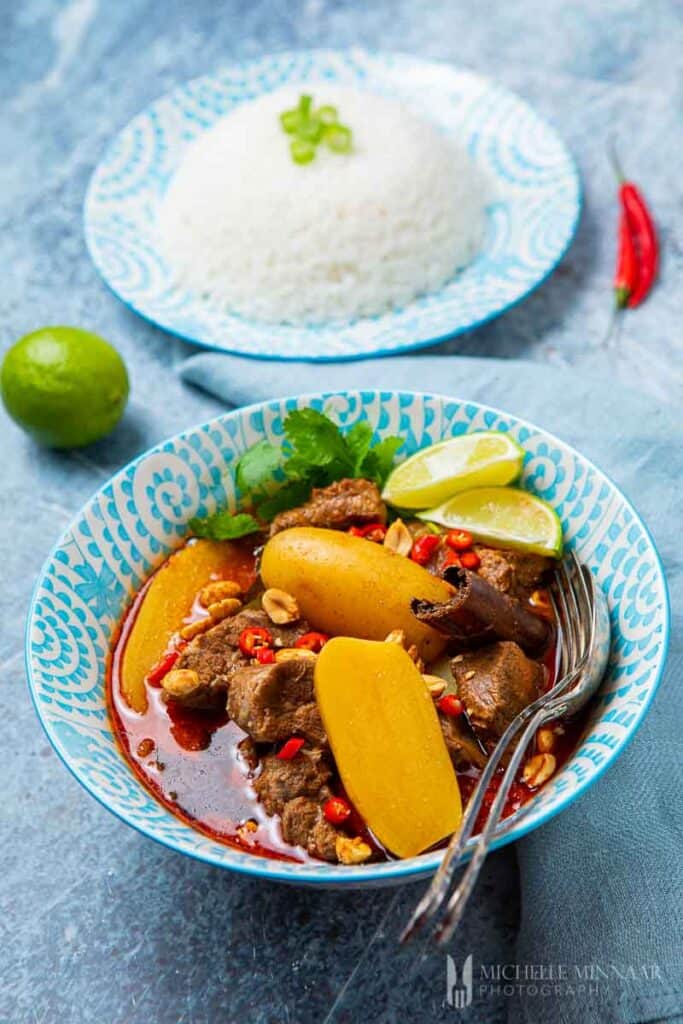 Close up of lamb curry and bowl of white rice