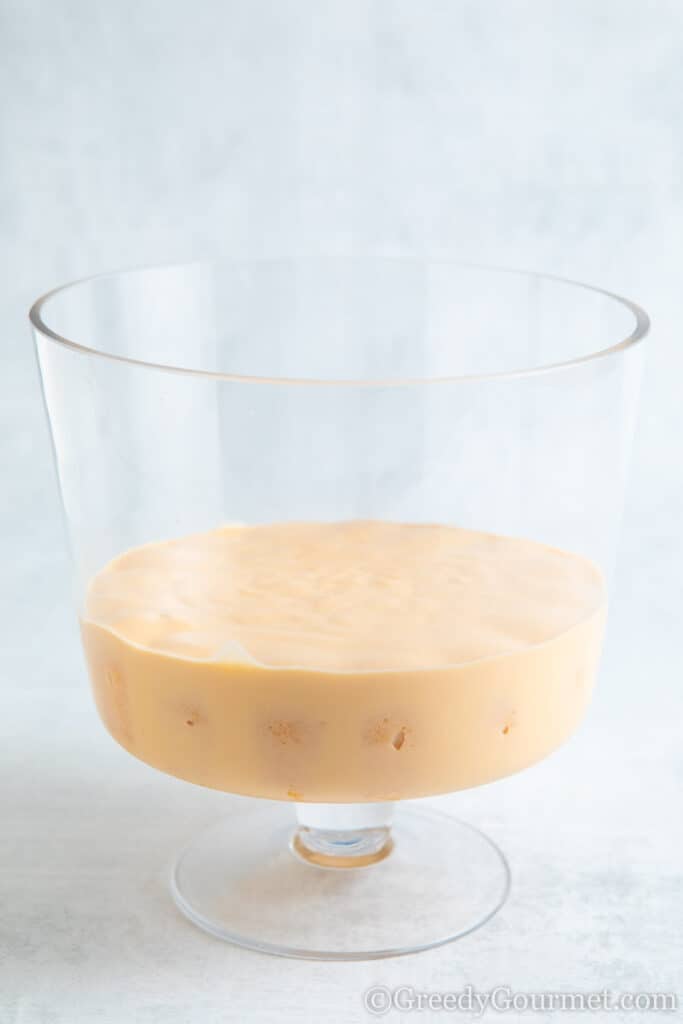 Custard poured over the biscuits in the clear glass