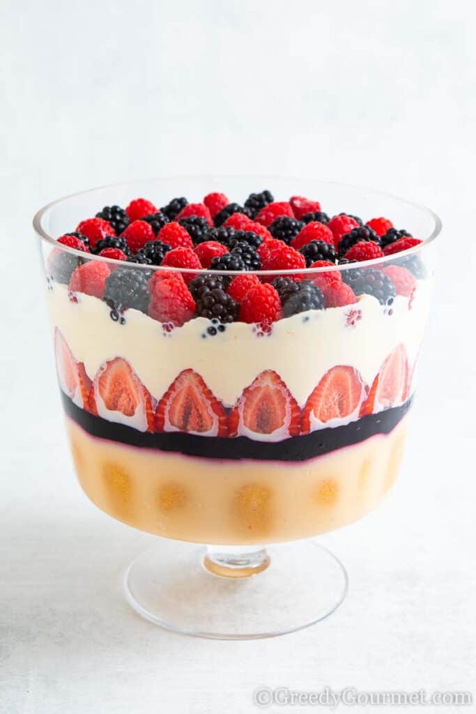 Multiple layers of a berry trifle dessert with fresh berries