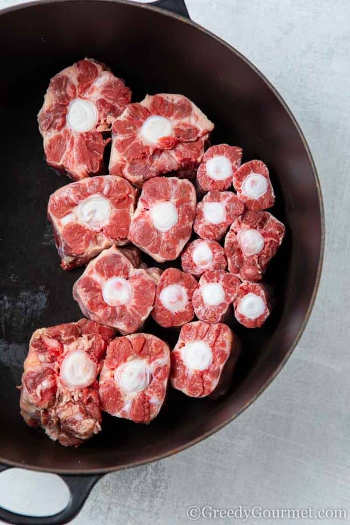 Raw oxtail cooking in a pan