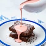 Pink custard being poured onto a chocolate cake