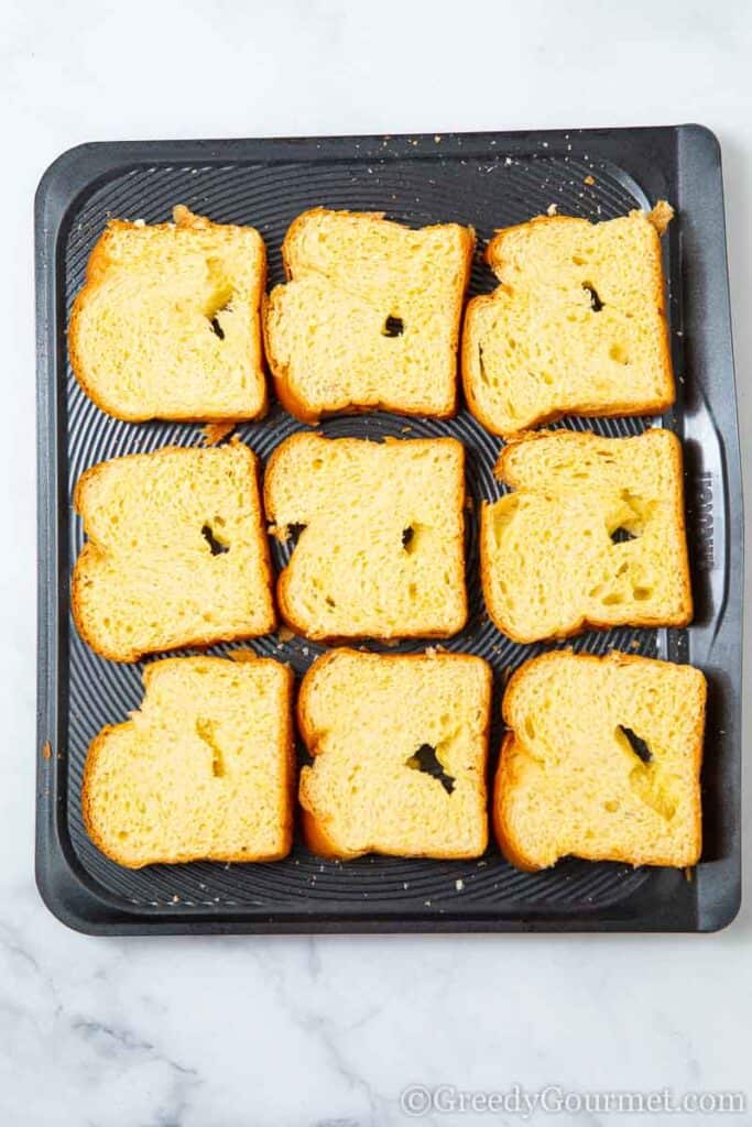 Nine slices of brioche bread on a baking pan