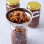 Jam being funneld into a jar to make a plum recipe