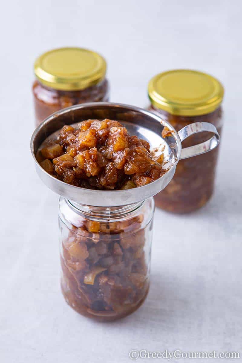 Jam being funneld into a jar to make a plum recipe