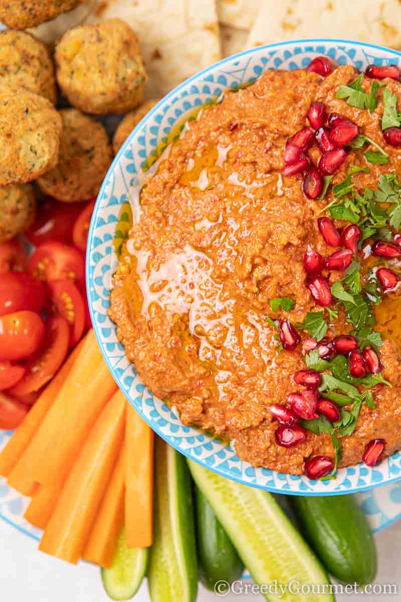 Bowl of bright orange muhammara (roasted red pepper dip)