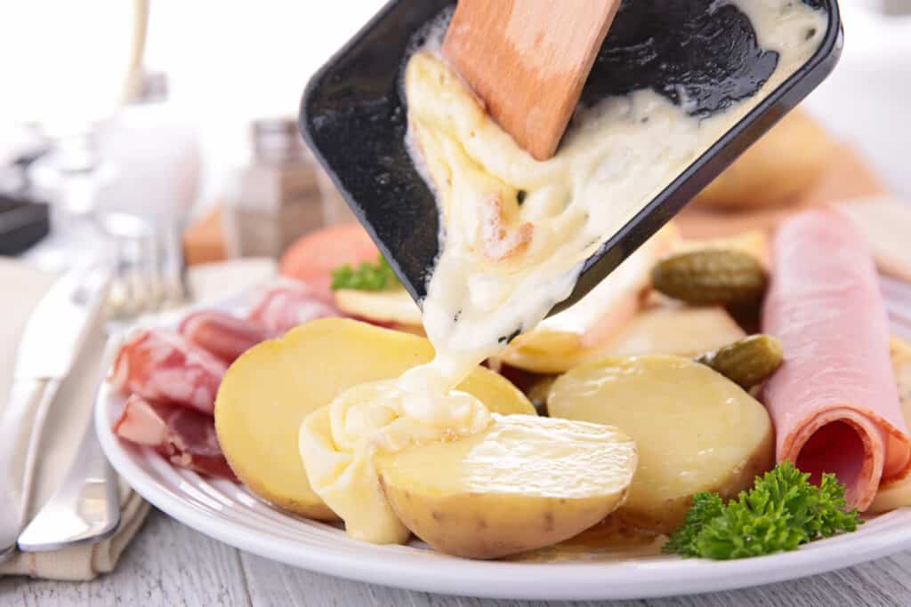 Melted raclette cheese bring poured over potatoes