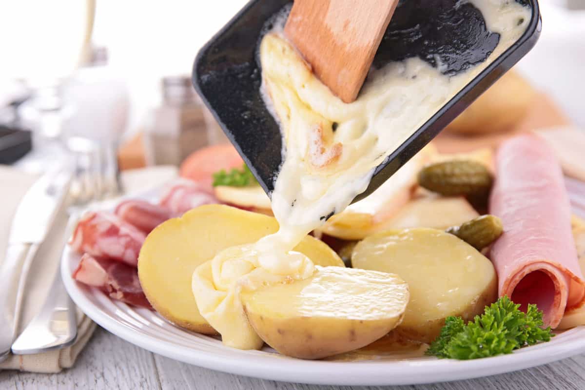 Melted raclette cheese, a type of swiss cheese, bring poured over potatoes.