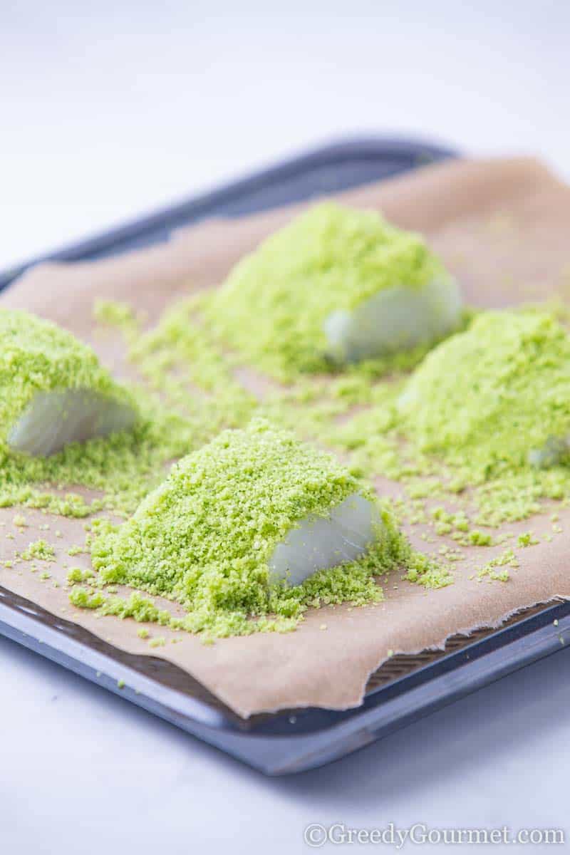 Raw cod dusted with green crust ready to bake