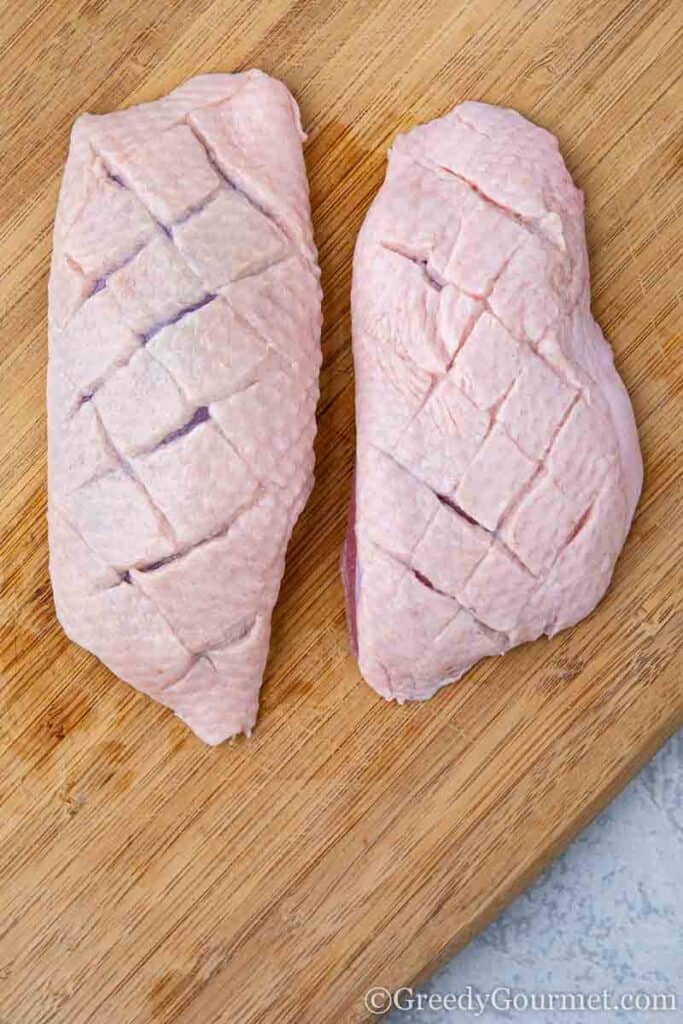 two scored raw duck breasts