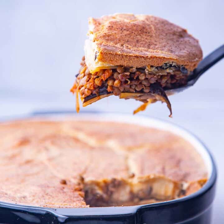 Slice of vegan moussaka being removed from a casserole dish