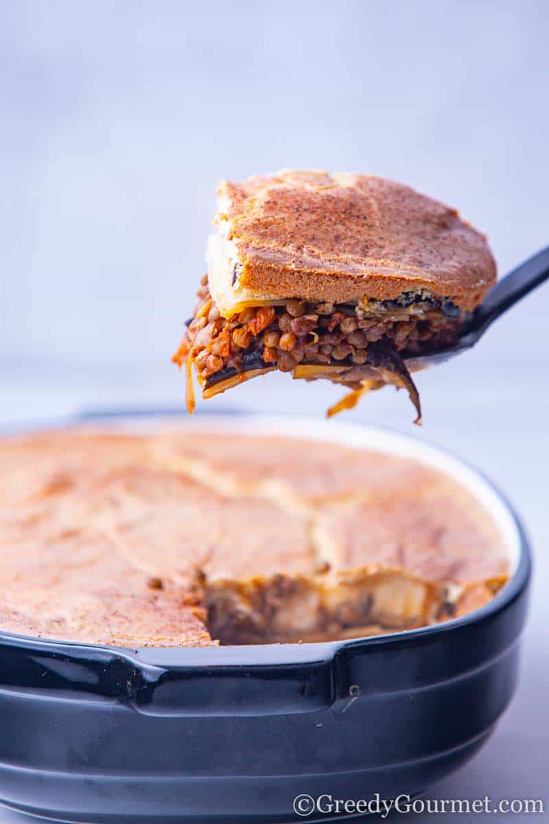 Slice of vegan moussaka being removed from a casserole dish