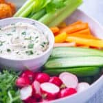 Bowl of white creamy vegan ranch dressing and fresh cut vegetables