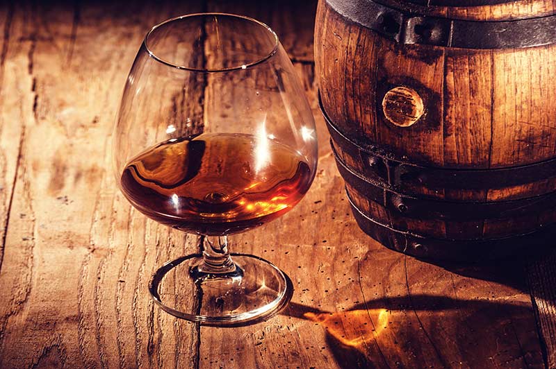Small pour of cognac and a wooden barrel