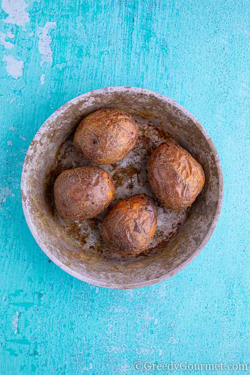 Four baked potatoes in a bowl