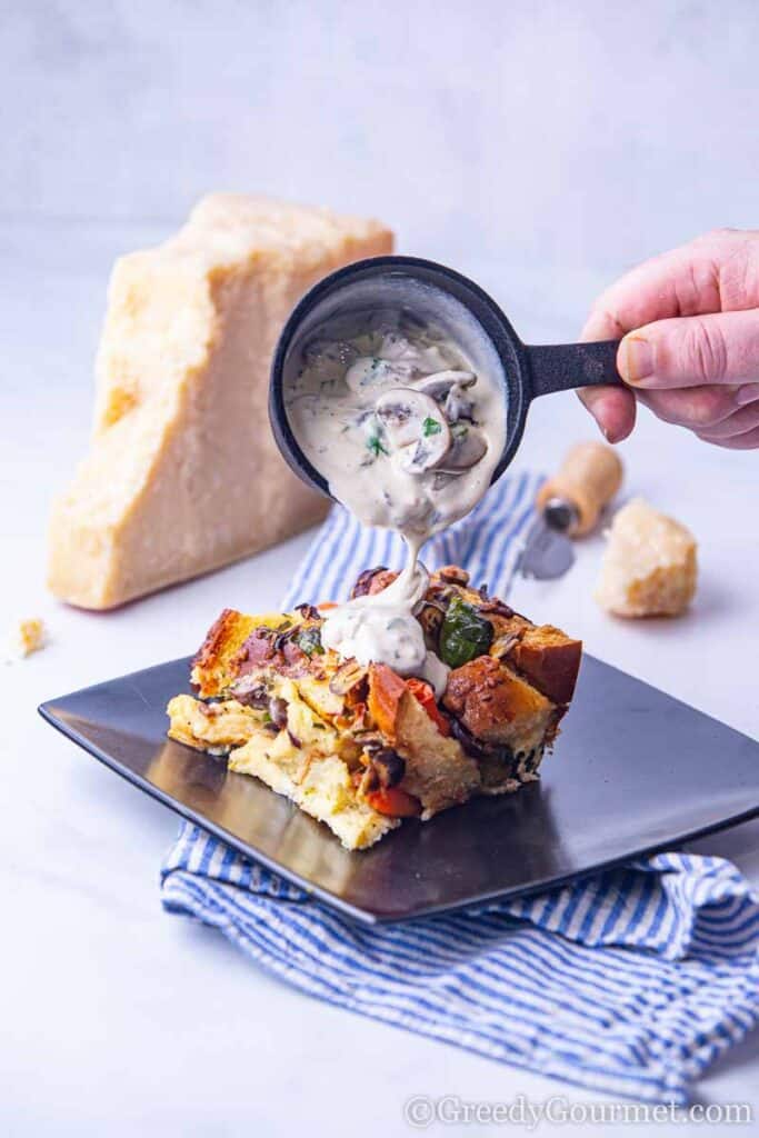 Mushroom sauce being poured onto bread pudding