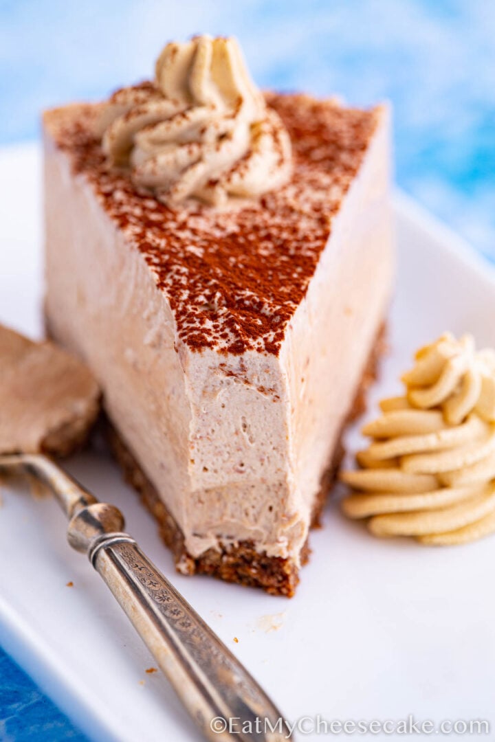 no bake mocha cheesecake slice decorated with cocoa powder and whipped cream spirals.