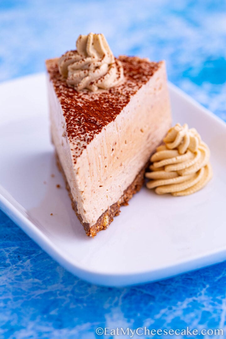 no bake mocha cheesecake slice decorated with cocoa powder and whipped cream spirals.