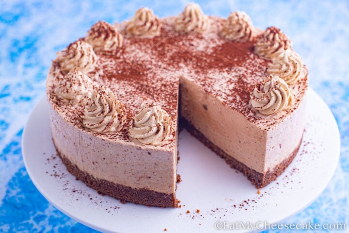 no bake mocha cheesecake decorated with cocoa powder and whipped cream spirals.