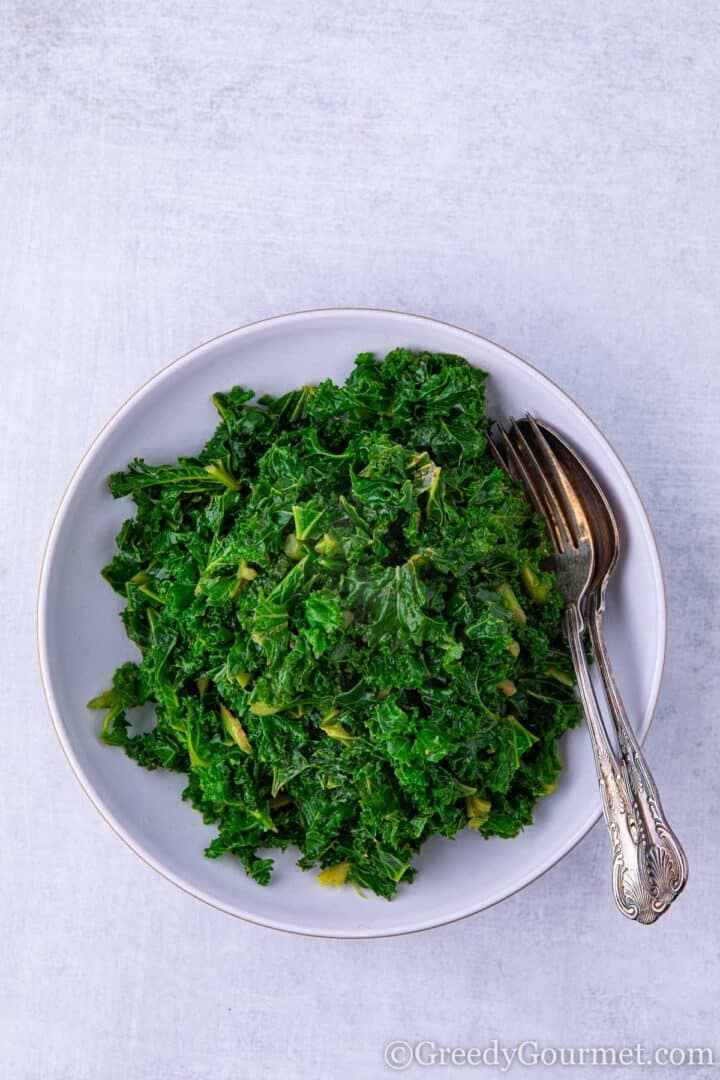 Blanched kale in bowl with knife and spoon