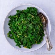 Fresh bowl of bright green kale with fork and spoon