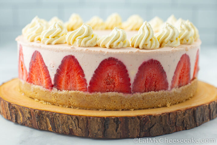 Side view of a strawberry cheesecake decorated with cream.
